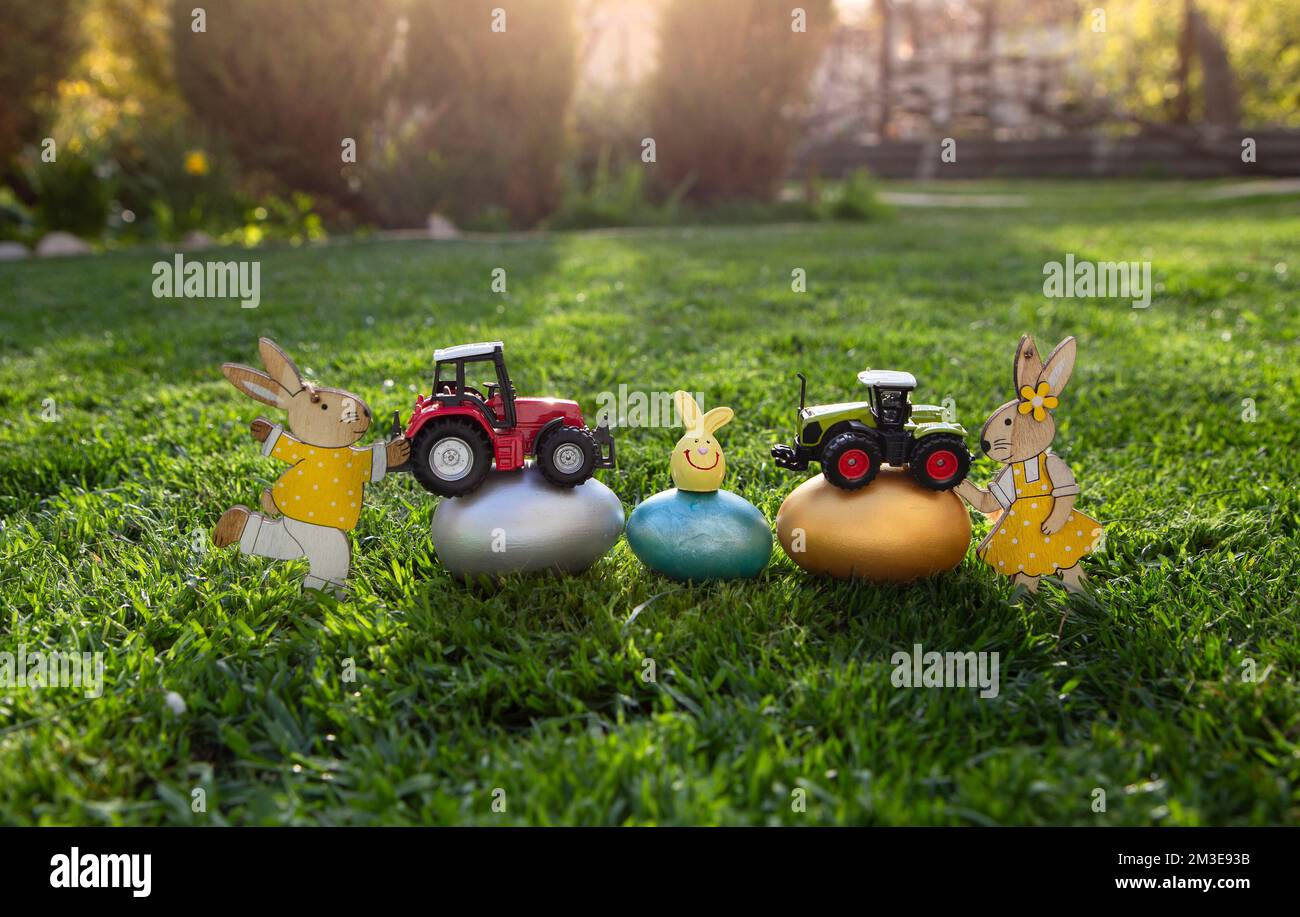 modèles de jouets modèles de deux tracteurs, oeufs aux couleurs vives et lapins de pâques se trouvent sur l'herbe. Concept d'affaires pour Pâques salutations pour l'agriculture et Banque D'Images
