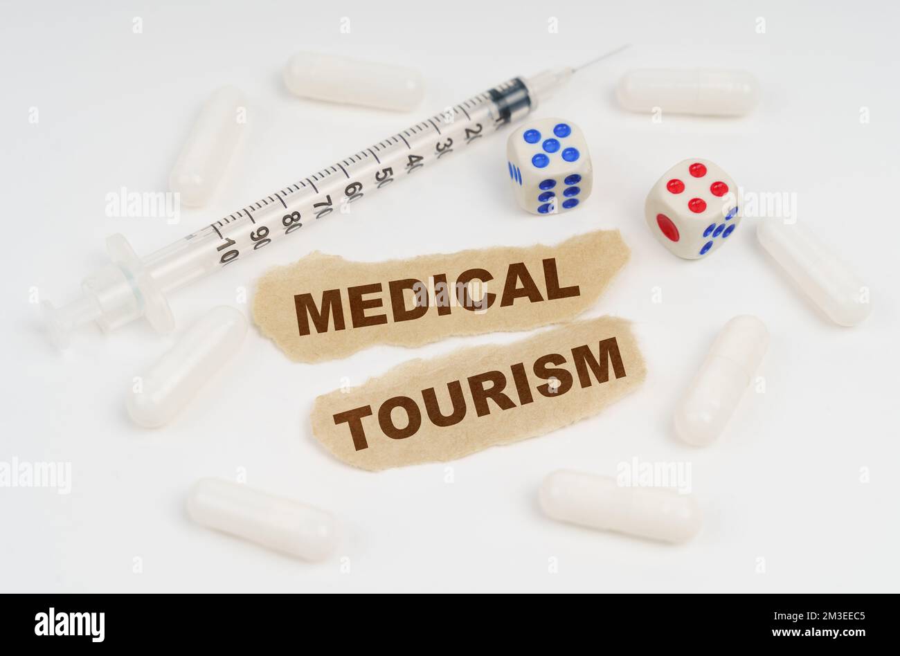 Concept médical. Sur une surface blanche se trouve une seringue, des pilules, des dés et des morceaux de papier avec l'inscription - MEDICAL TOURISM Banque D'Images