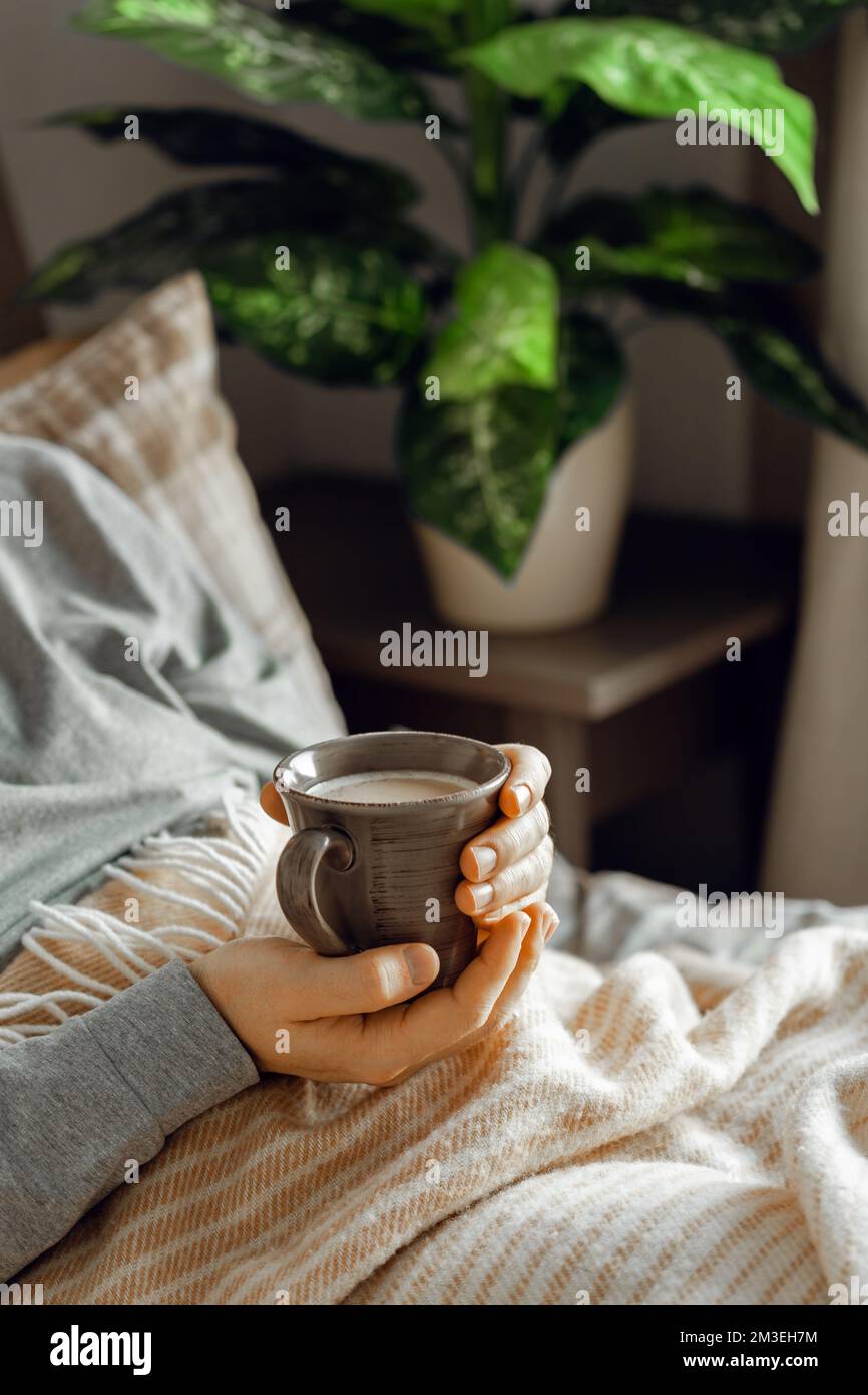 un homme caucasien se reposant à la maison, buvant du café au lit Banque D'Images