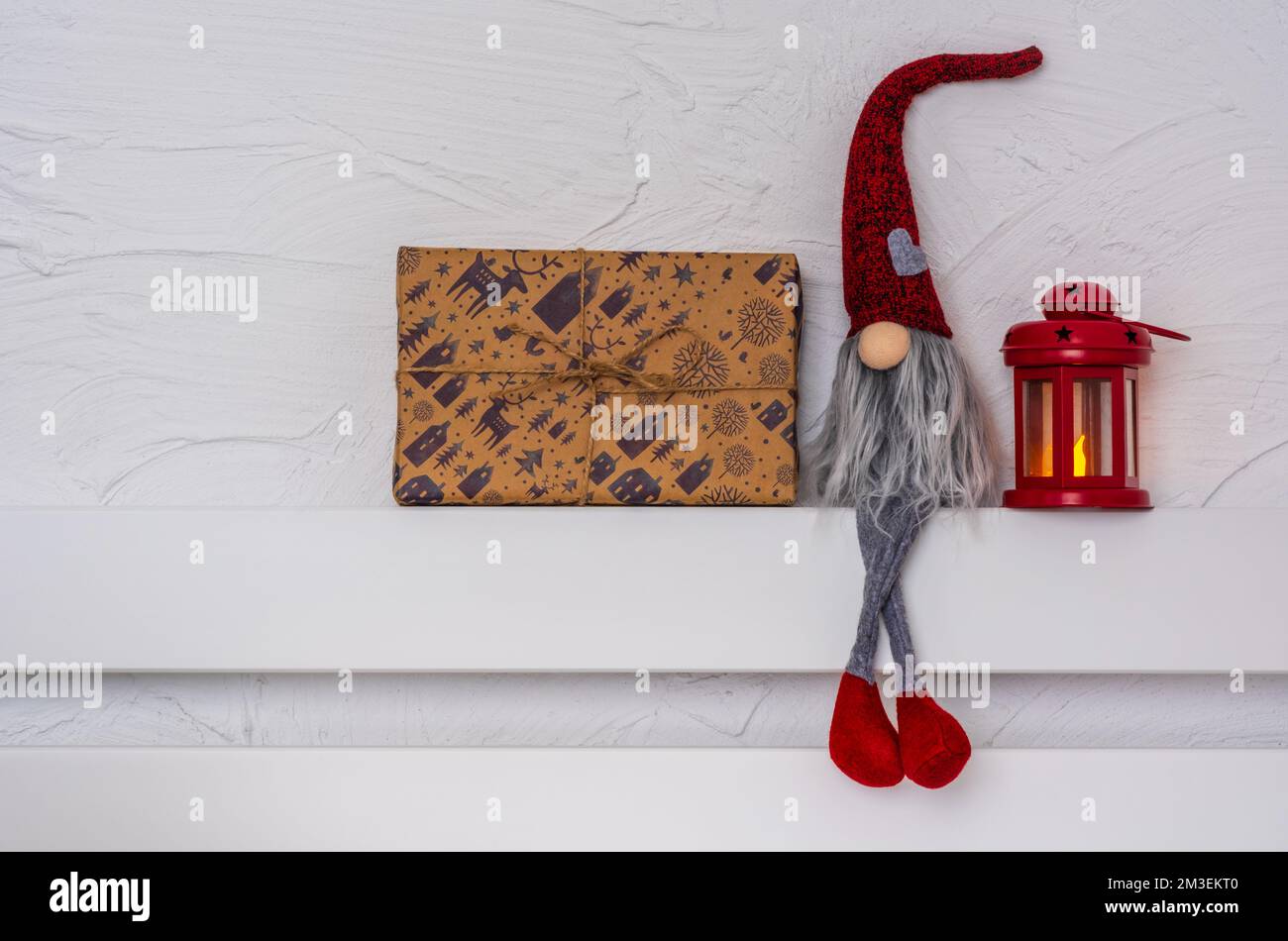 Christmas Gnom - Gonk avec une longue barbe et un chapeau rouge assis sur la tablette en bois blanc avec pattes de suspension. Concept Noël et nouvel an, carte de vœux, Banque D'Images