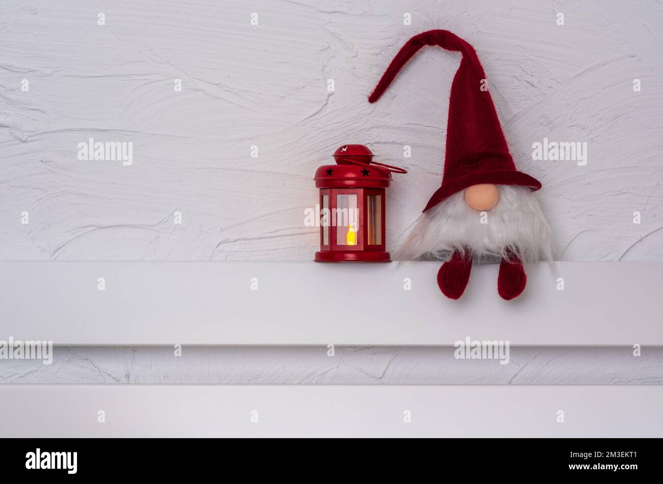 Christmas Gnom - Gonk avec une longue barbe et un chapeau rouge assis sur la tablette en bois blanc avec pattes de suspension. Concept Noël et nouvel an, carte de vœux, Banque D'Images