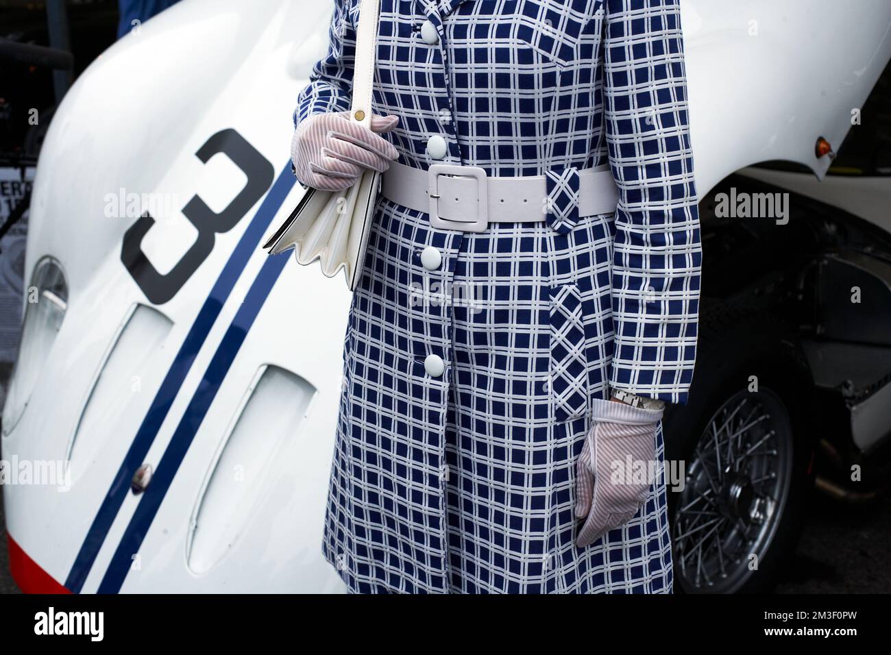 Femme méconnaissable posant avec une voiture de course à Goodwood Revival, Royaume-Uni . Banque D'Images