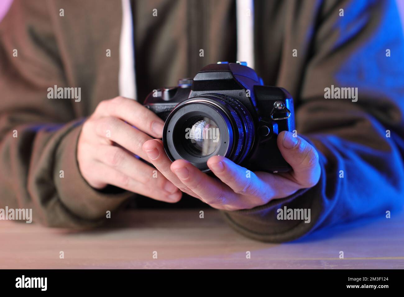 appareil photo numérique avec ancien objectif manuel dans les mains sur la table et sur fond coloré Banque D'Images