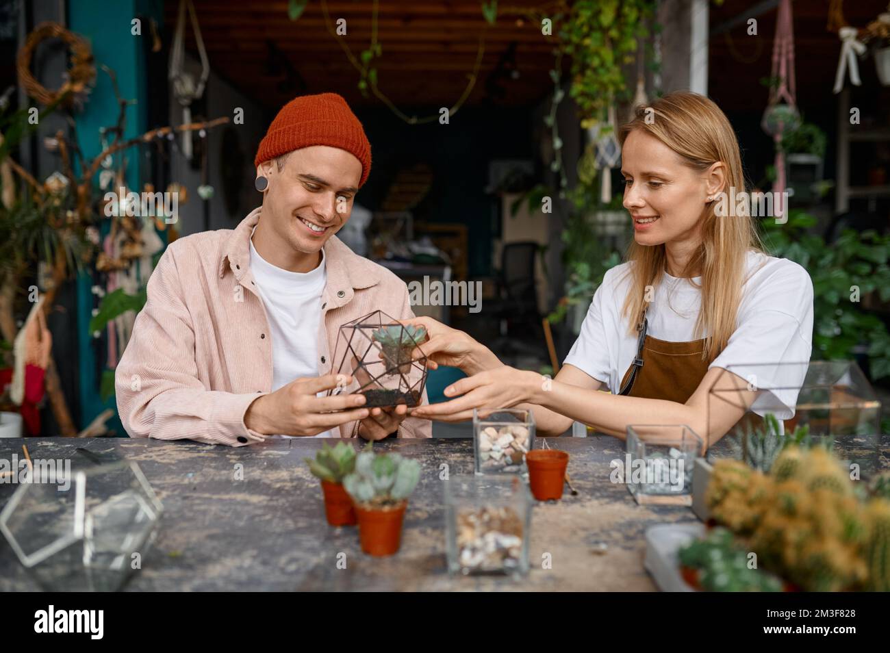 Homme heureux et femme faisant la composition dans le vase de florarium Banque D'Images