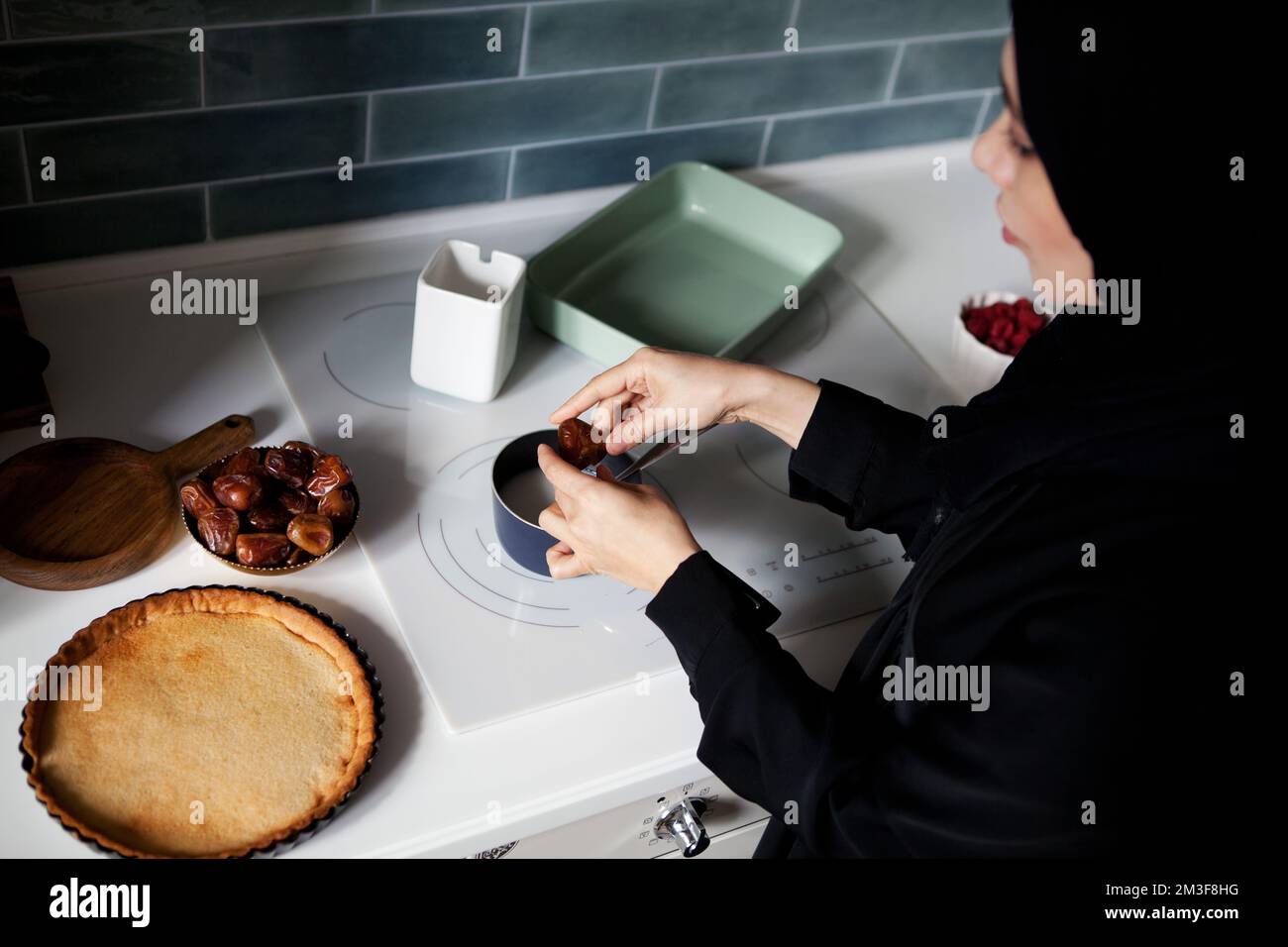 Femme arabe cuisant le gâteau sur le poêle blanc dans la cuisine maison,  porte l'abaya noir et hijab Photo Stock - Alamy