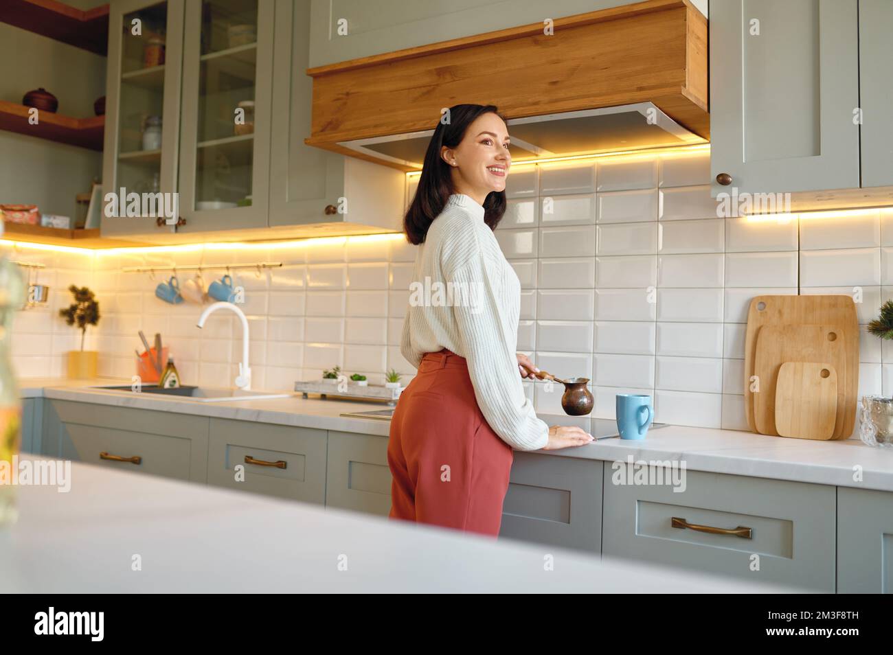 Bonne jeune femme qui prépare du café dans une tasse de café sur la cuisine Banque D'Images