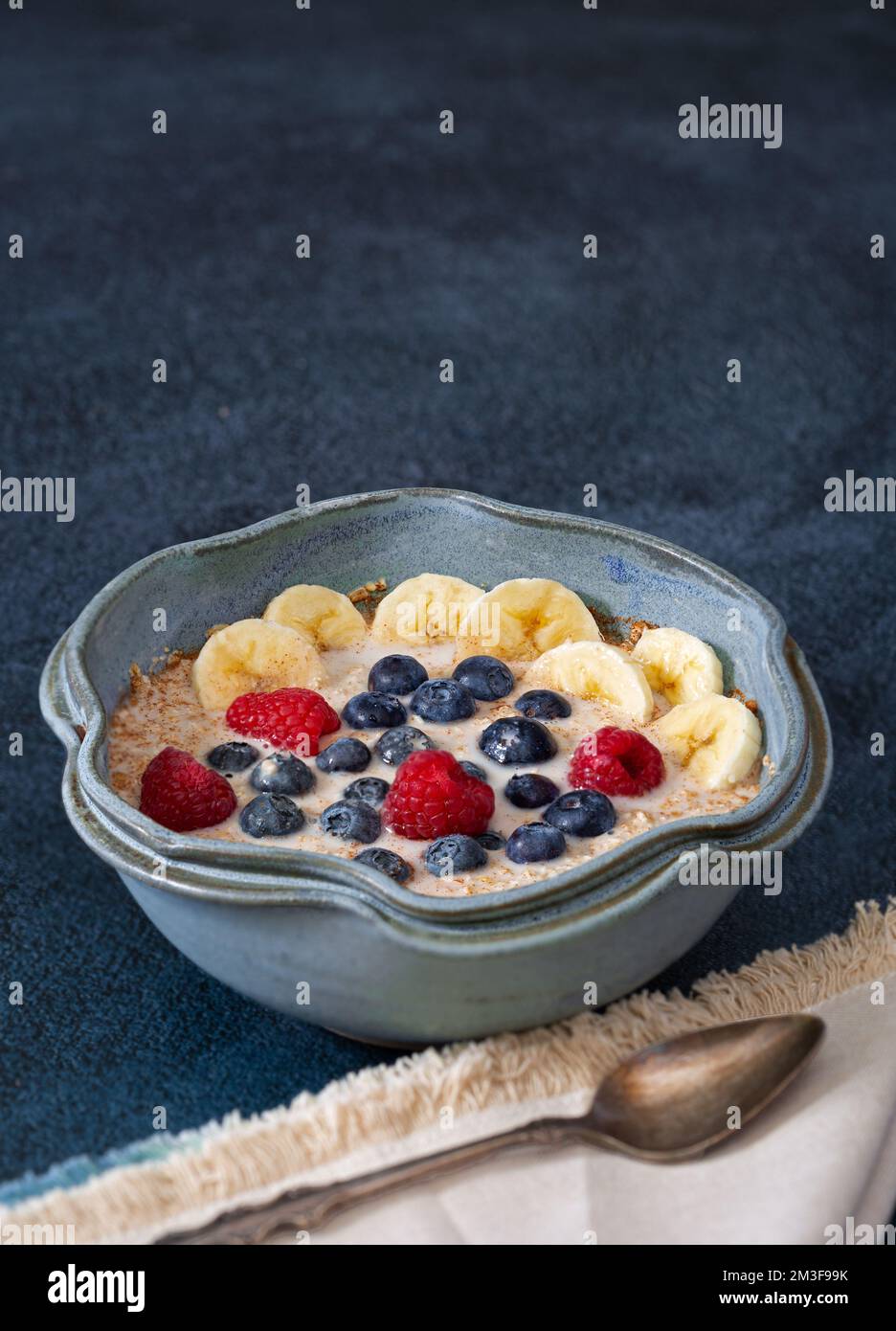Petit déjeuner à base de plantes d'avoine coupée en acier, recouvert de banane, de bleuets, de framboises, mélangé avec du lait d'amande Banque D'Images