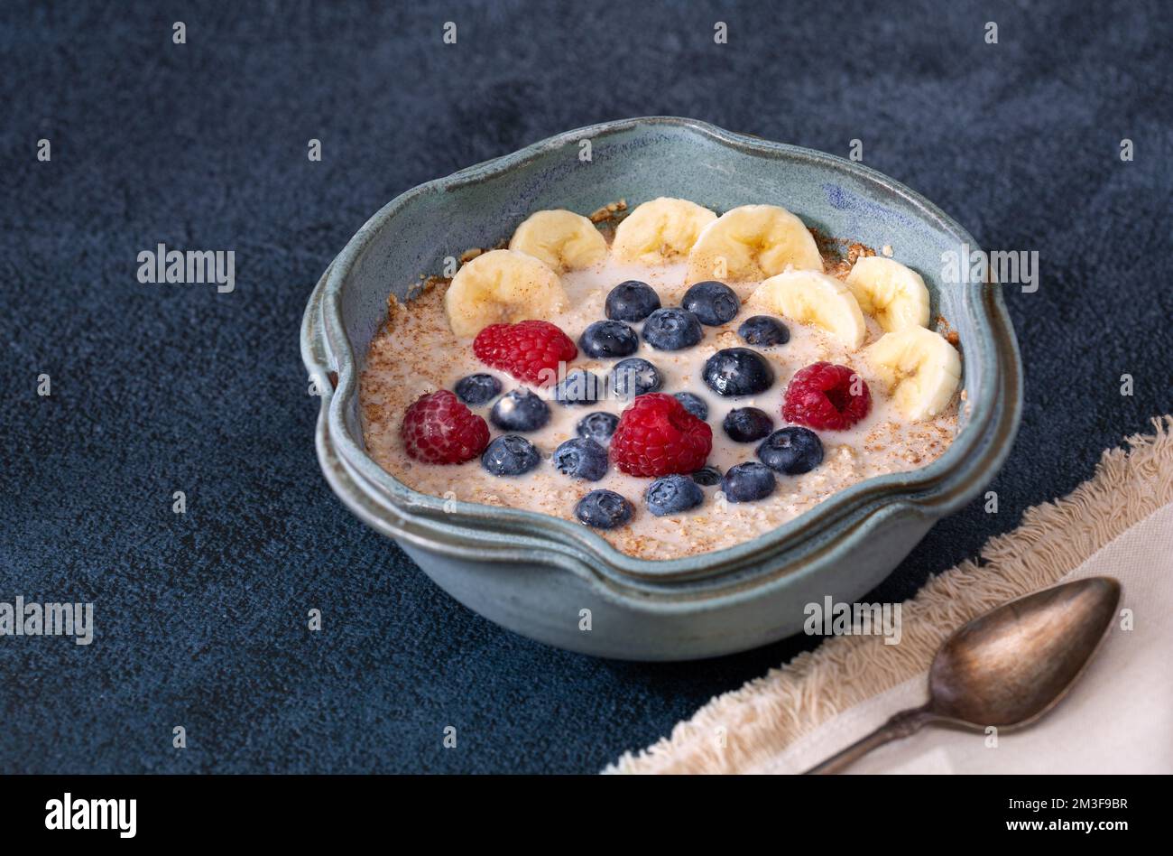 Petit déjeuner à base de plantes d'avoine coupée en acier, recouvert de banane, de bleuets, de framboises, mélangé avec du lait d'amande Banque D'Images
