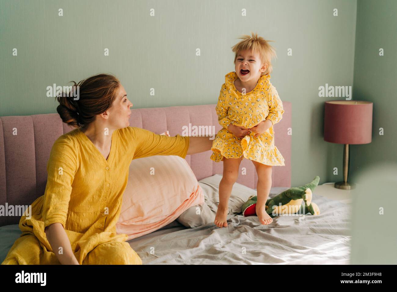 Maman et petite fille gaie et petite fille ont du plaisir dans la chambre sur le lit. Banque D'Images