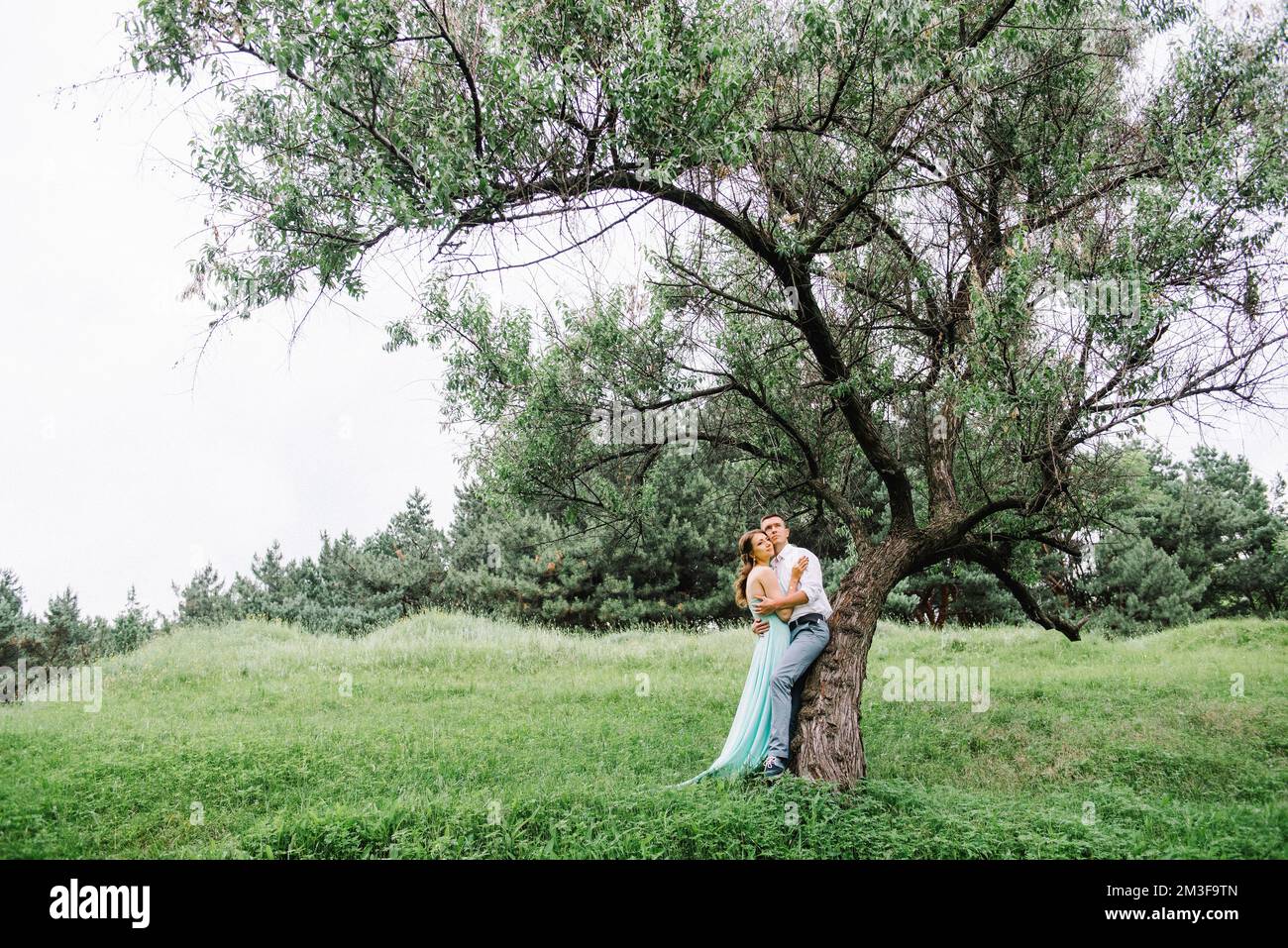 un homme heureux dans une chemise blanche et une fille dans une robe  turquoise, la mariée et le marié marchent dans le parc forestier Photo  Stock - Alamy