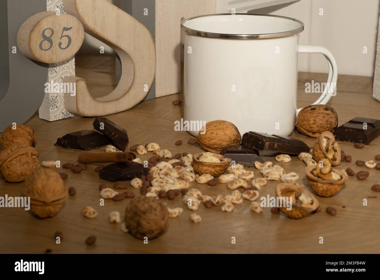 Un gros plan de noix et de chocolats avec une tasse blanche sur une table en bois Banque D'Images