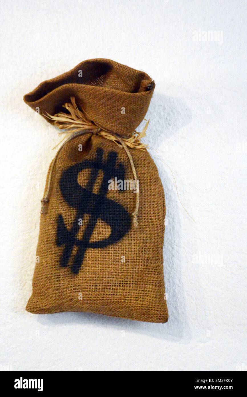 Sac de banque complet avec affiche en dollars américains sur un mur blanc Banque D'Images