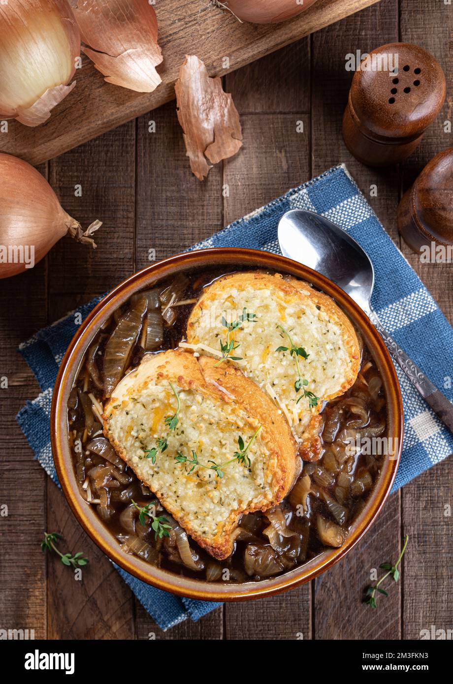 Soupe à l'oignon français avec baguette au fromage grillé garnie de thym sur fond rustique de table en bois Banque D'Images