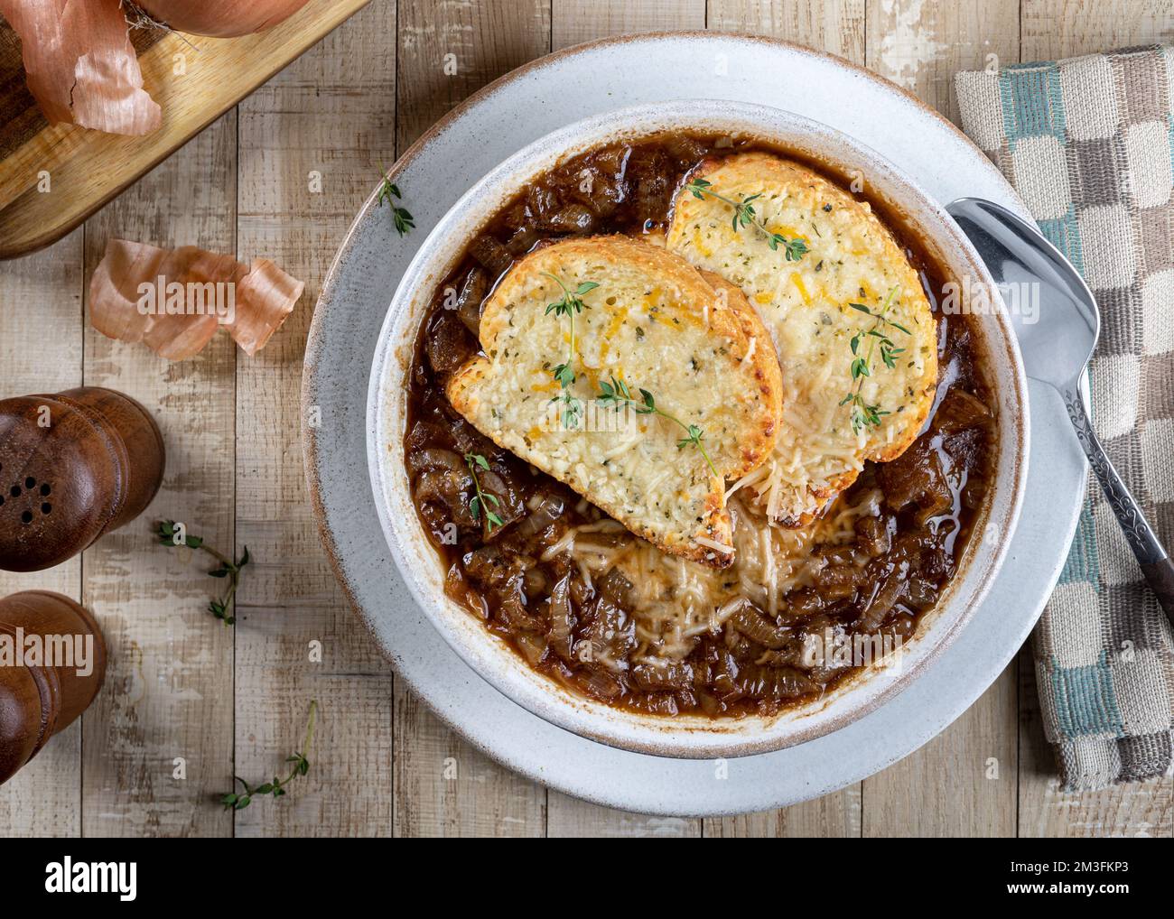 Soupe à l'oignon français avec baguette au fromage grillé garni de thym sur une table rustique en bois, vue sur le dessus Banque D'Images