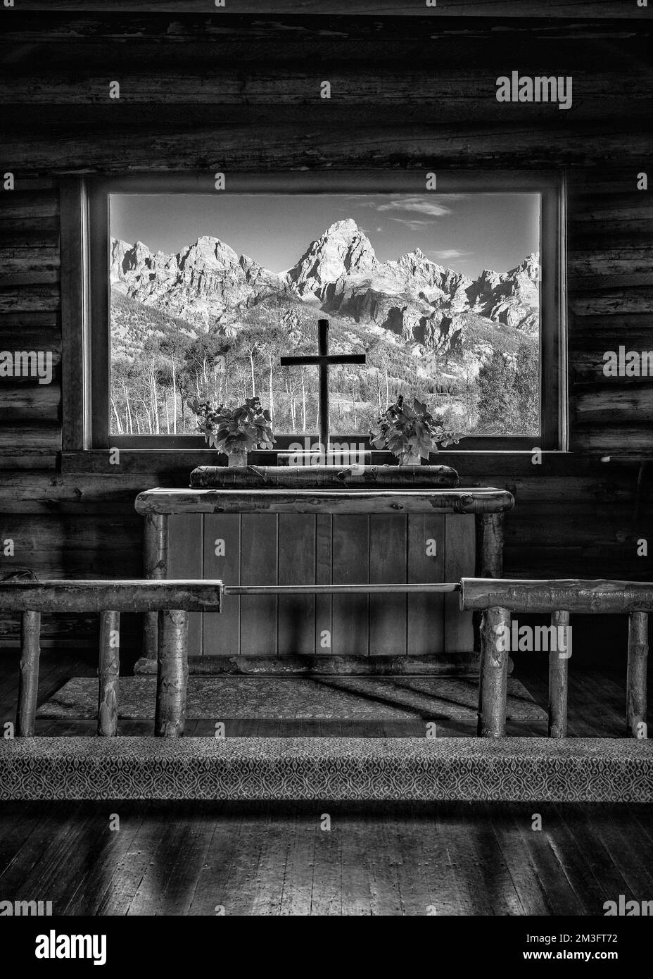 Montagnes à travers une fenêtre en verre au-dessus de l'autel de la chapelle historique de la Transfiguration dans le parc national de Grand Teton près de Moose, Wyoming Banque D'Images