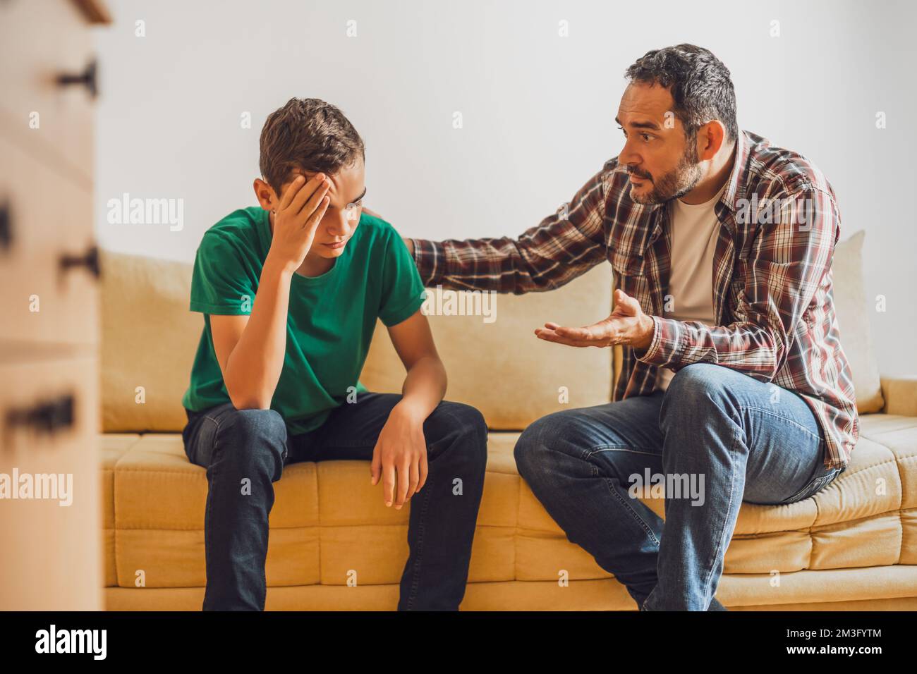 Le père et le fils parlent à la maison. Son fils a des problèmes et son père le consoler. Banque D'Images