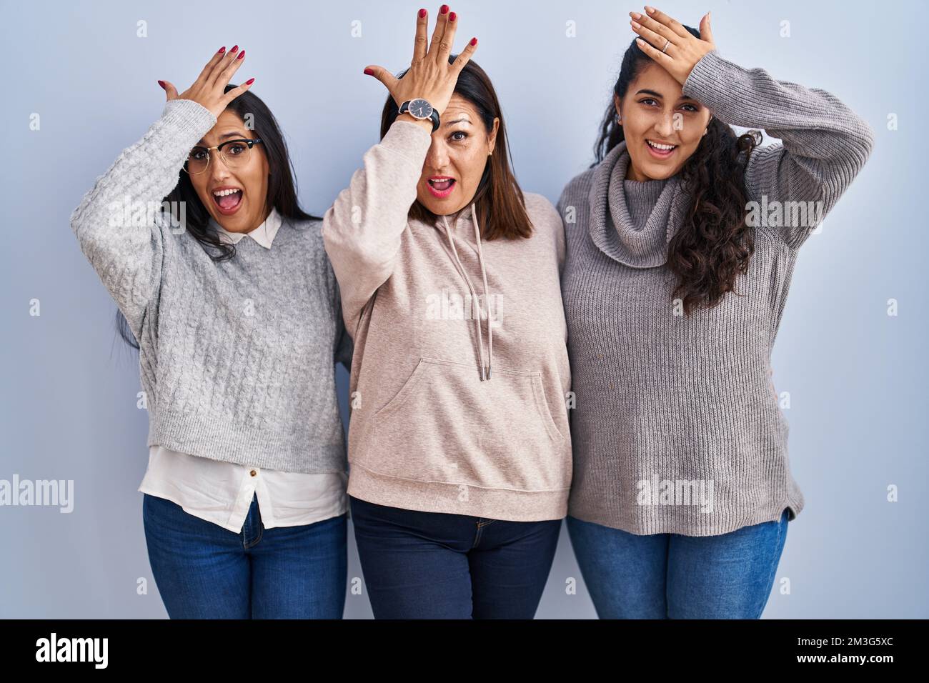 Mère et deux filles debout sur fond bleu surpris avec la main sur la tête pour erreur, se souvenir de l'erreur. oubli, mauvais concept de mémoire. Banque D'Images Mère et deux filles debout sur fond bleu surpris avec la main sur la tête pour erreur, se souvenir de l'erreur. oubli, mauvais concept de mémoire. Banque D'Images