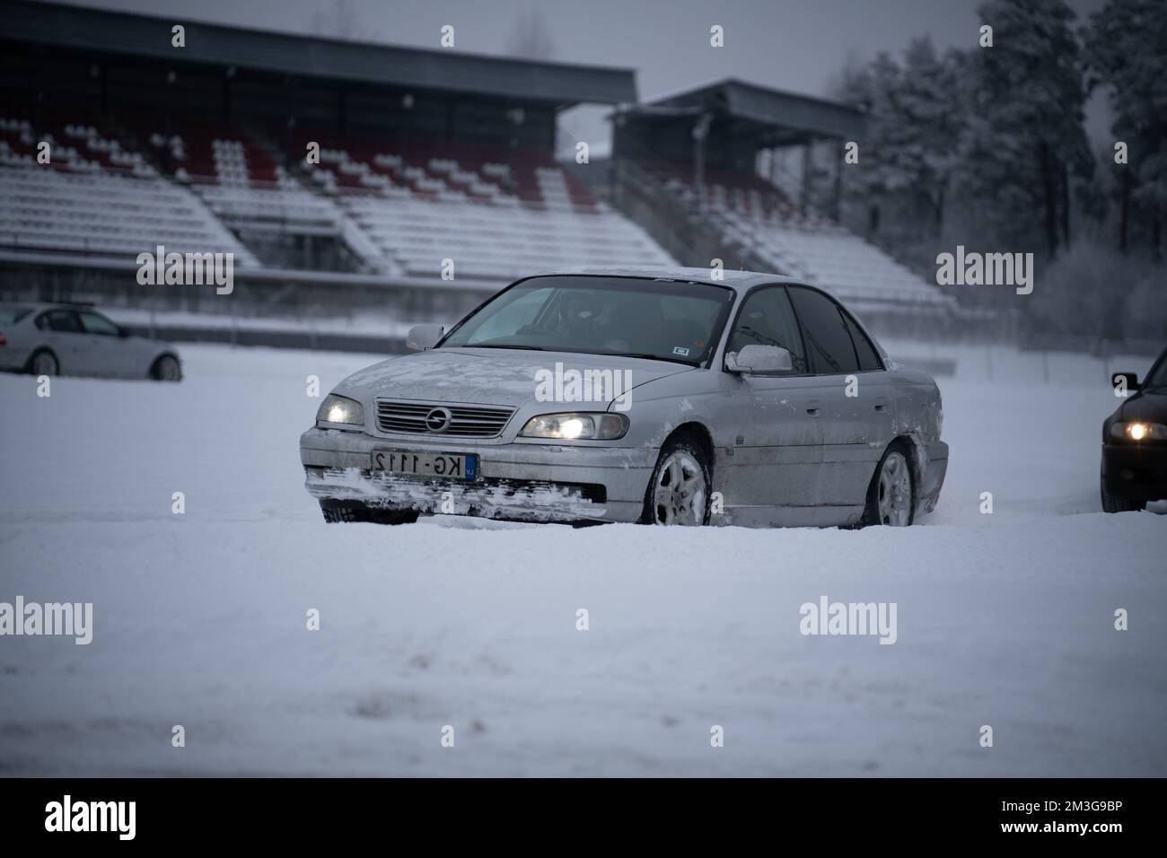 12-12-2022 Riga, Lettonie une voiture traverse la neige près d'un stade en arrière-plan. . Banque D'Images