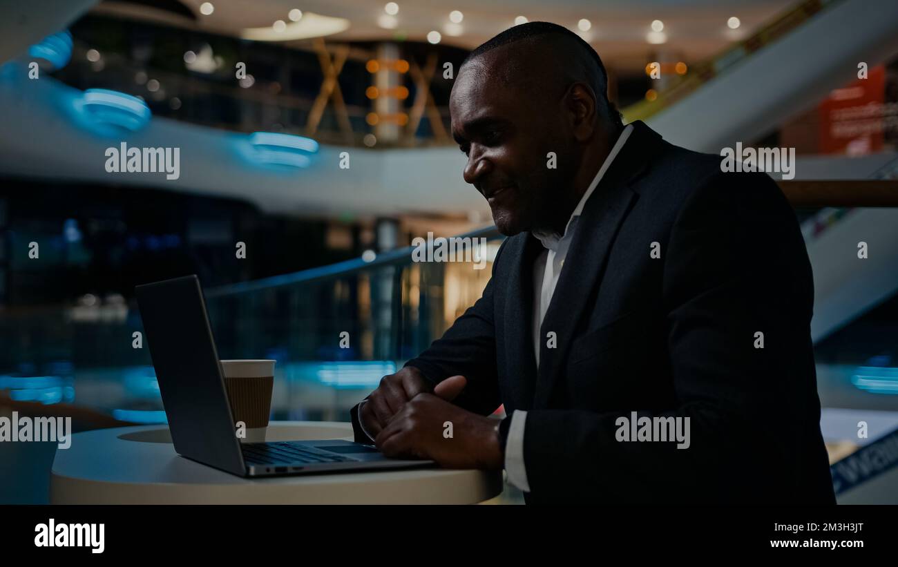 Homme ethnique de 50s ans, responsable d'un travailleur africain tapant un ordinateur sans fil à table. Adulte senior homme d'affaires mature travaillant avec un portable mâle Banque D'Images
