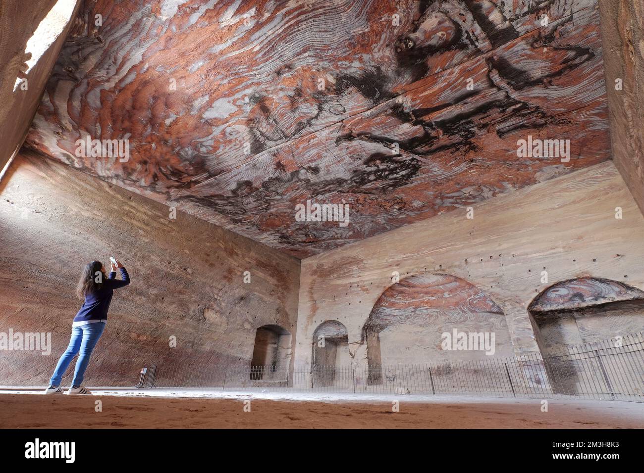 Un touriste prenant des photos des murs de la tombe de la soie, Petra, Jordanie, superbes tourbillons de différentes couleurs de roche. Banque D'Images