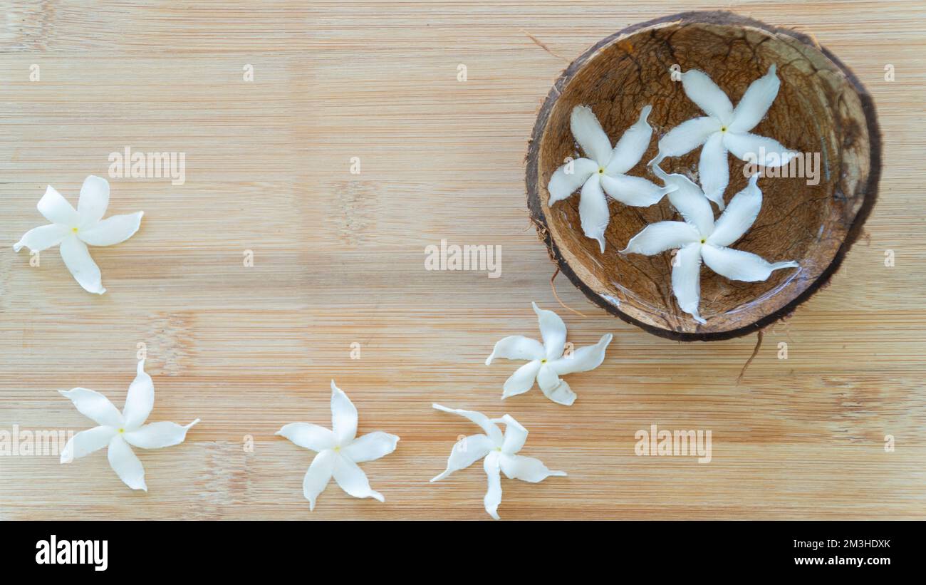 Fleurs blanches dans l'eau dans un bol de noix de coco sur fond de bois Banque D'Images