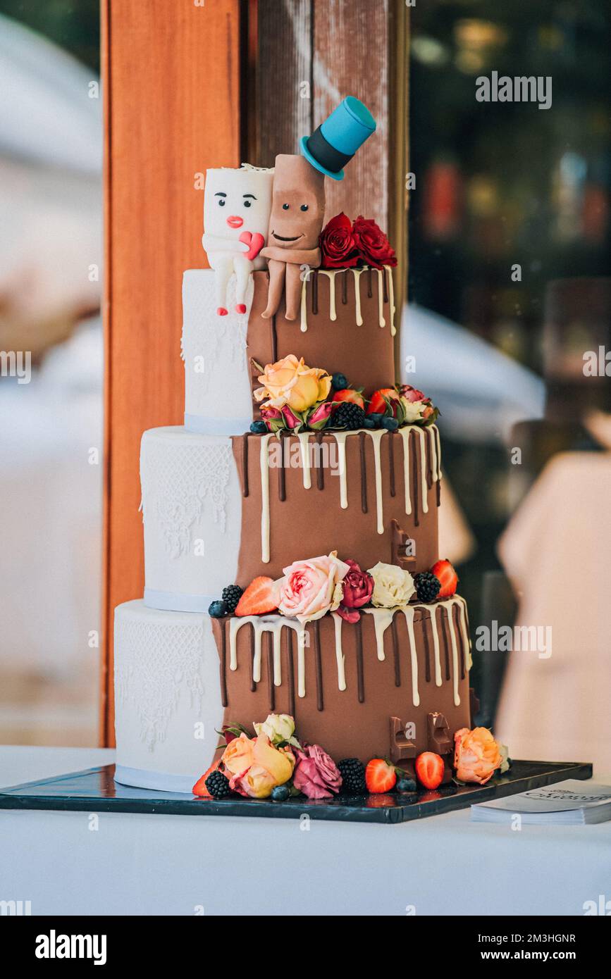 Une photo verticale d'un gâteau de mariage demi-brun demi-blanc décoré de baies et de fleurs Banque D'Images