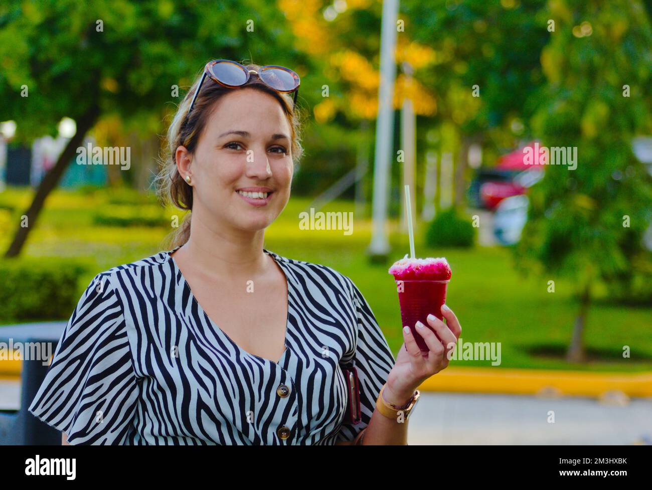 fille avec boisson rafraîchissante à la main, derrière le paysage vert Banque D'Images