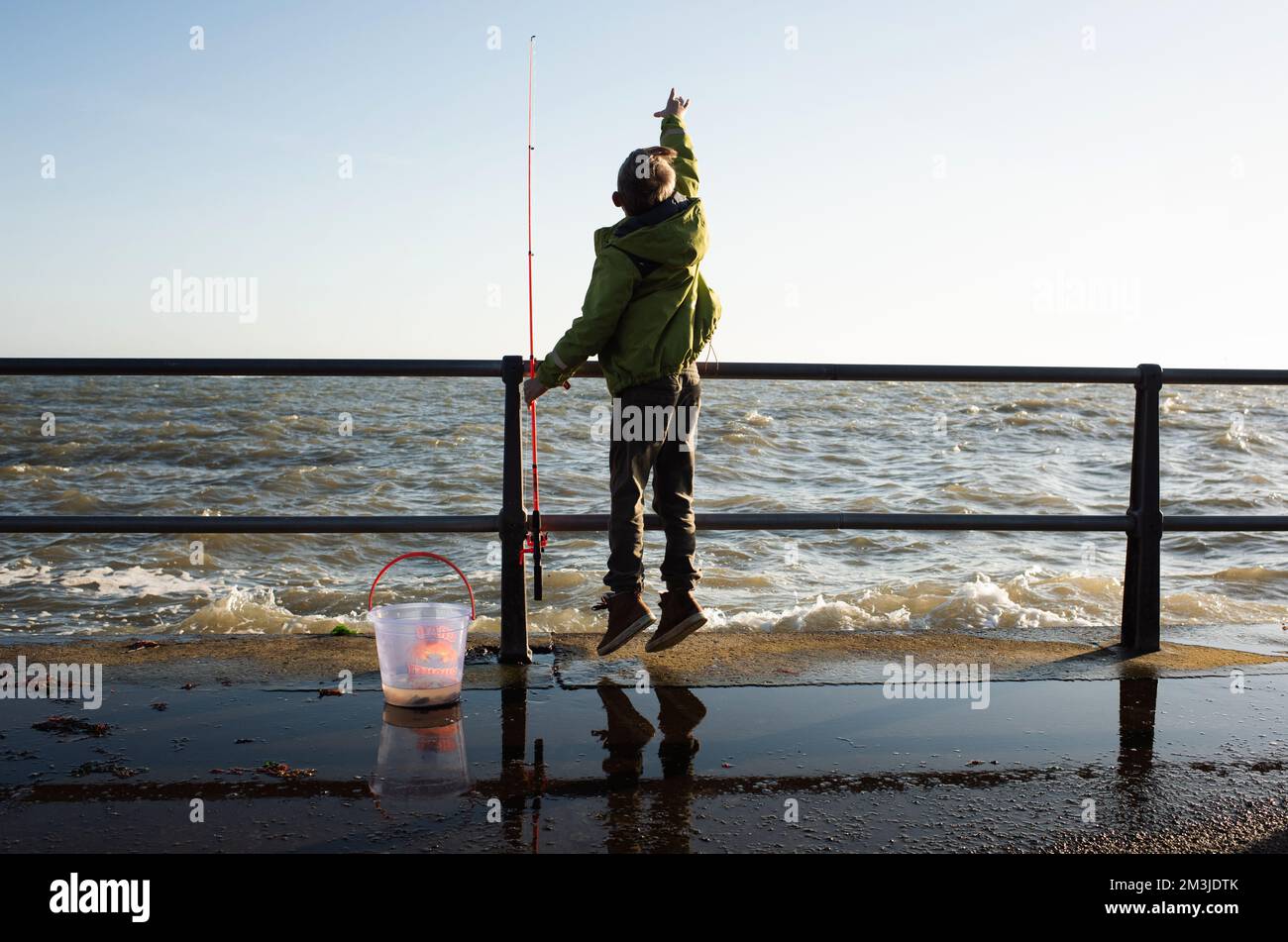 un garçon pêche aux crabes sur le quai au bord de la mer Banque D'Images