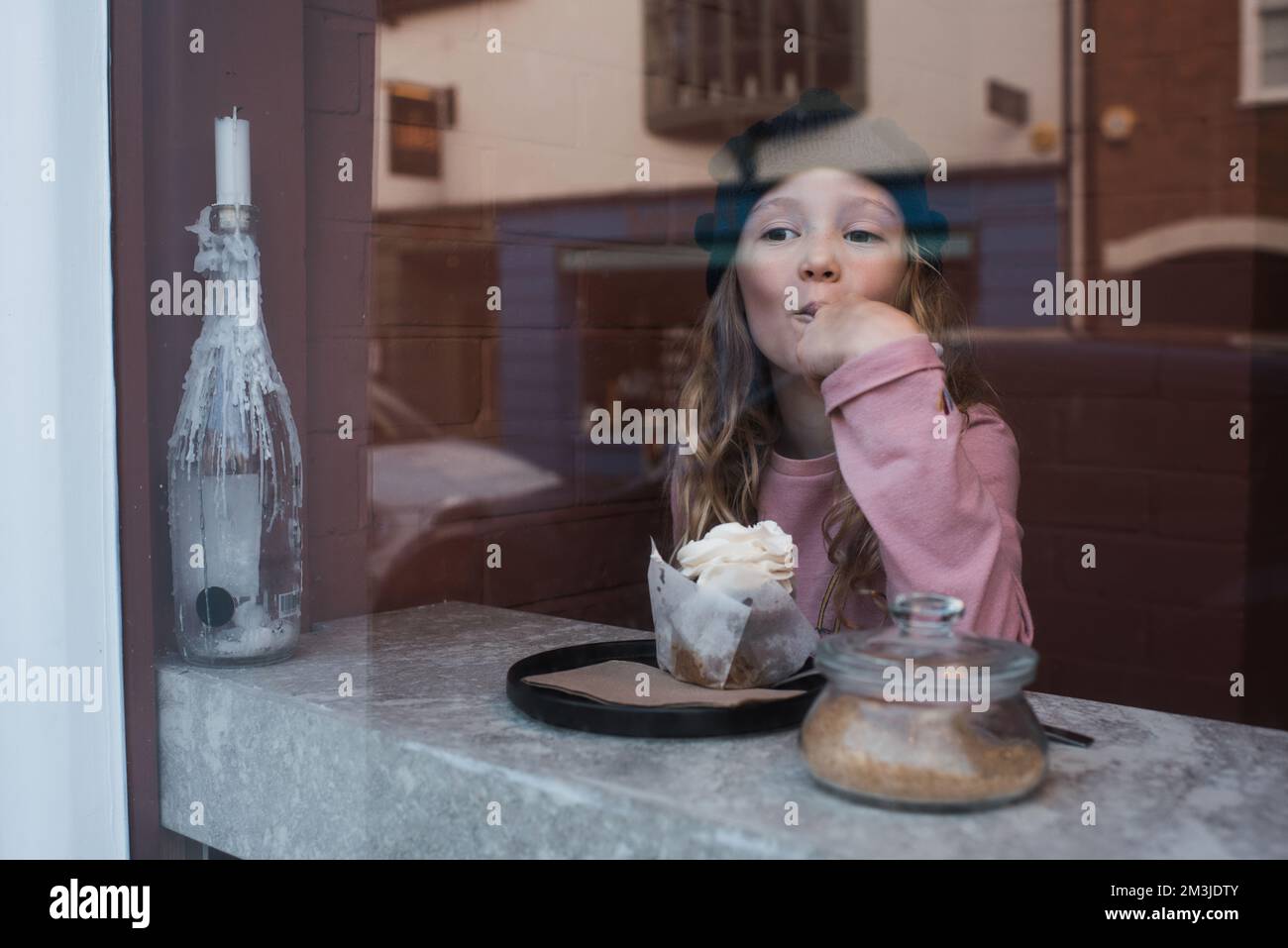une jeune fille s'est assise dans un café en mangeant du gâteau et en buvant du chocolat chaud Banque D'Images