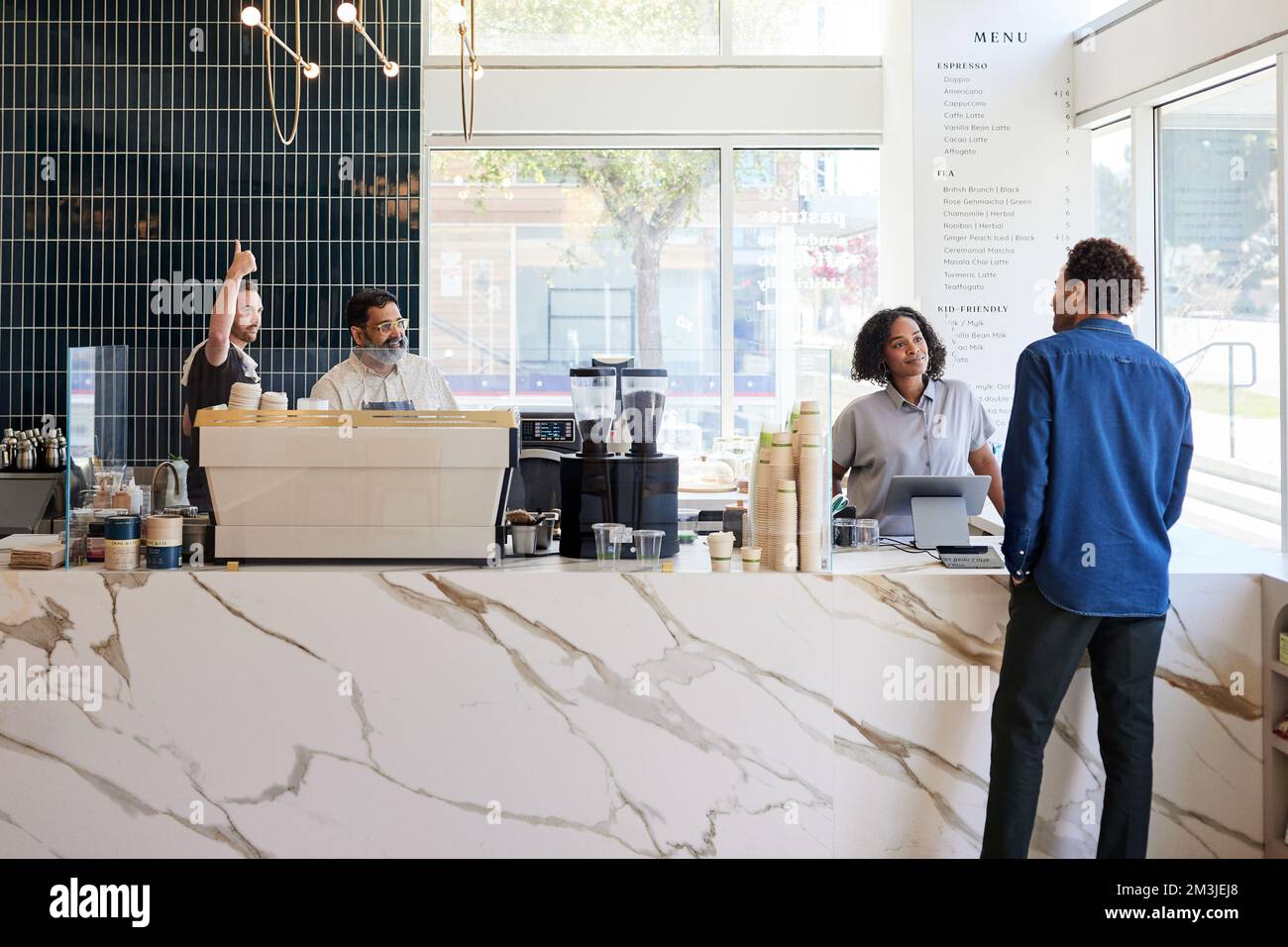 Un client de sexe masculin parle au personnel de la cuisine du café-restaurant Banque D'Images