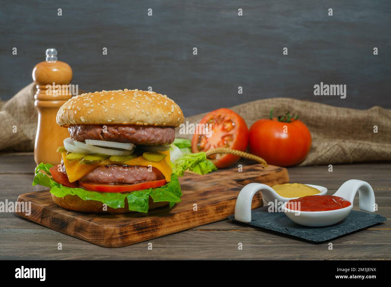 délicieux hamburger complet sur une planche de bois et des sauces Banque D'Images