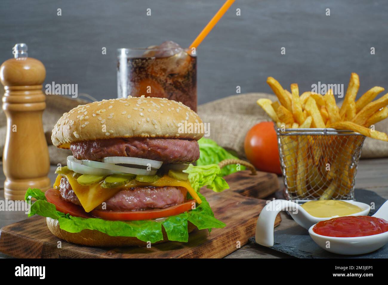hamburger complet avec deux viandes, sauces, frites et soda au cola. Banque D'Images