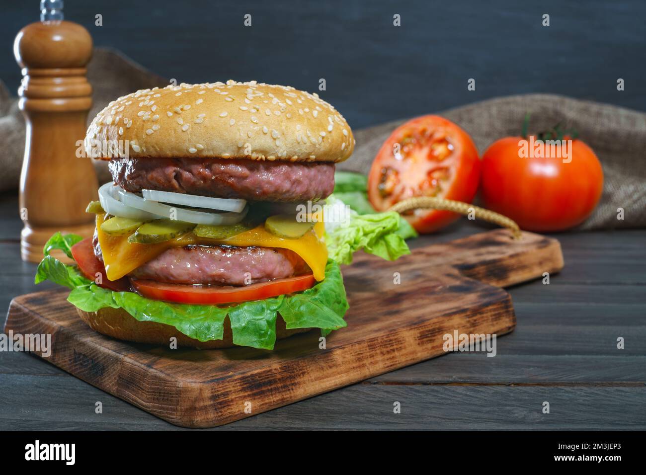 délicieux hamburger complet sur une planche de bois et des sauces Banque D'Images