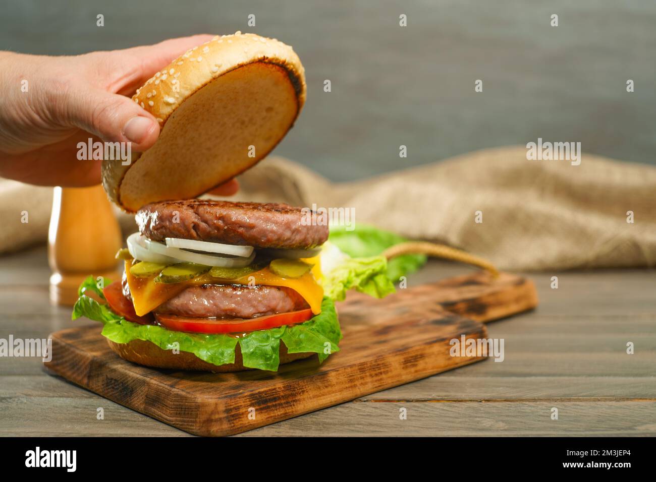 femme ouvrant le petit pain d'un hamburger avec deux morceaux de viande Banque D'Images