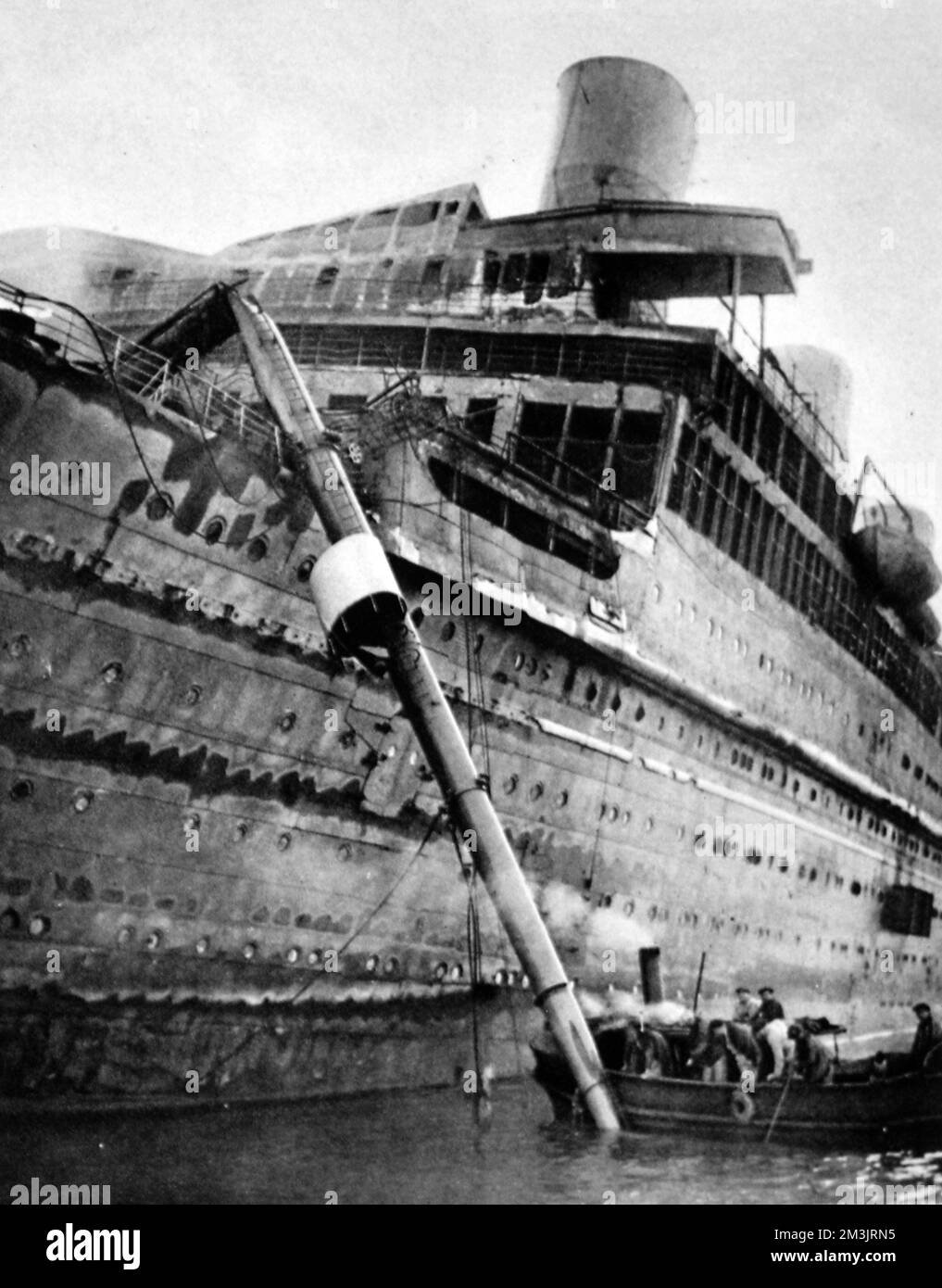Le paquebot brûlé, l'Atlantique, a été introduit avec succès dans le port de Cherbourg. L'incendie a éclaté dans les premières heures du 4th janvier 1933, à 6am l'ordre d'abandon de navire a été donné. Le paquebot n'avait pas de passagers à bord, seulement l'équipage, beaucoup ont été pris dans le bateau à vapeur britannique, Ford Castle. Un canot de sauvetage a été jeté dans la mer, noyant certains des occupants. Pendant des heures, la doublure brûlée s'est dissipée, la chaleur extraordinaire a empêché les bateaux de clavetage de s'approcher. Finalement, un navire français a sécurisé une ligne et l'a amenée à Cherbourg. Date: 1933 Banque D'Images