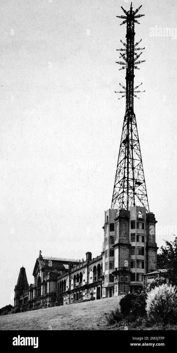 Alexandra Palace comme la maison du service de télévision B.B.C, montrant le mât et transmettant des antennes pour la vision et le son. Des tests spéciaux de réception du B.B.C d'Alexandra Palace de la télévision et du discours synchronisés ont été tenus à Olympia par un comité de l'Association des manufacturiers de radio. Les transmissions de jours alternés du palais Alexandra ont été données par les systèmes Baird et Marconi E.M.I. En 1935, le B.B.C expérimente le système de télévision de John Logie Baird et le système E.M.I de Marconi. L'E.M.I a succédé à Baird en 1937. 1936 Banque D'Images