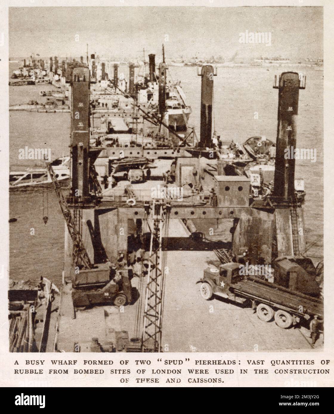 Un quai animé au port de 'Mullère', également connu sous le nom de 'Port Winston', au large d'Arromanches, en Normandie, 1944. Lorsque les armées alliées envahirent la Normandie en juin 1944, elles exigeaient l'utilisation d'un port pour décharger rapidement les approvisionnements. Les commandants alliés ont décidé de prendre un port préfabriqué, fait de caissons comme celui illustré, et du construire à Arromanches Beach. Banque D'Images
