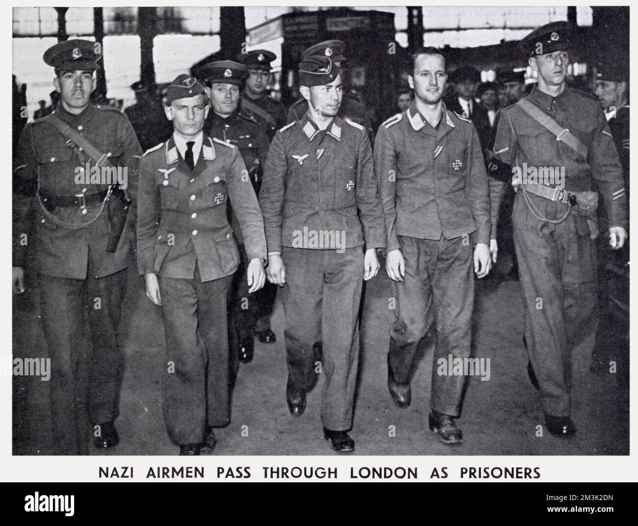 Trois membres de l'équipage (centre) allemands capturés sont en train d'être emparés par la police militaire britannique à travers une gare de Londres, en route vers un camp de prisonniers de guerre. Banque D'Images