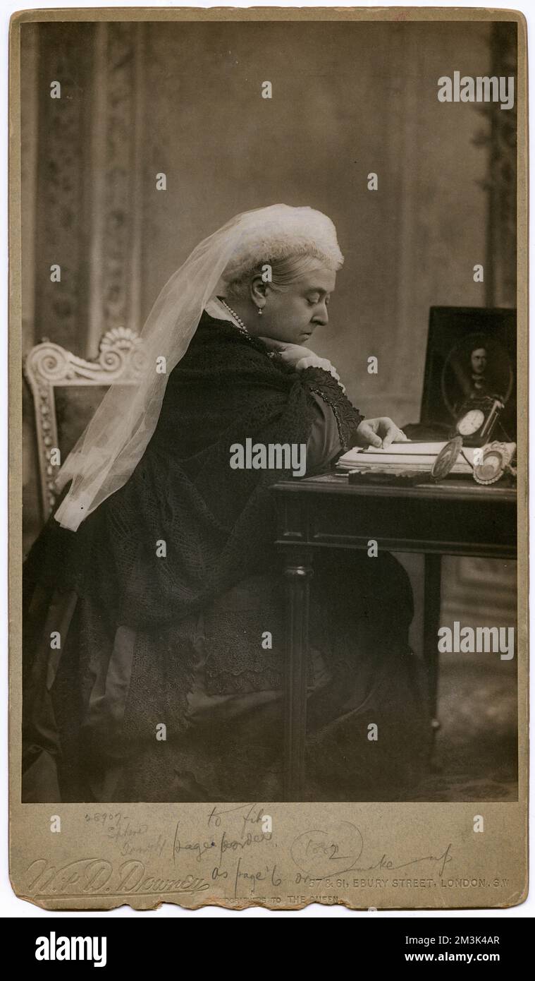 Étude photographique de la reine Victoria à son bureau de rédaction. Prise en 1882, un portrait encadré de son défunt mari, le Prince Albert, sur le bureau. Date: 1882 Banque D'Images
