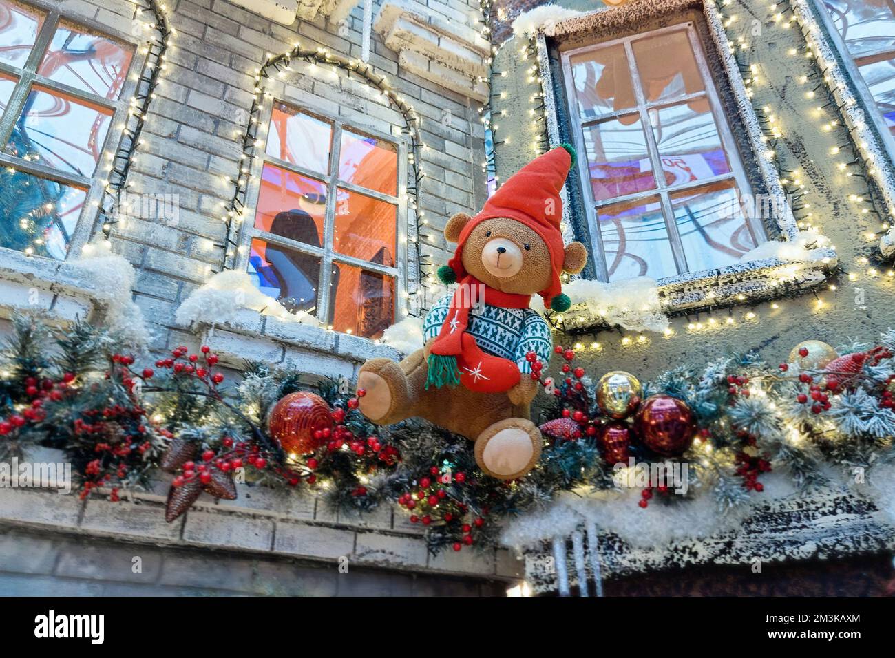 Les ours en peluche dans les chapeaux du Père Noël sont rampants sur le mur d'une maison décorée pour Noël. Le concept de Noël et du nouvel an. Banque D'Images