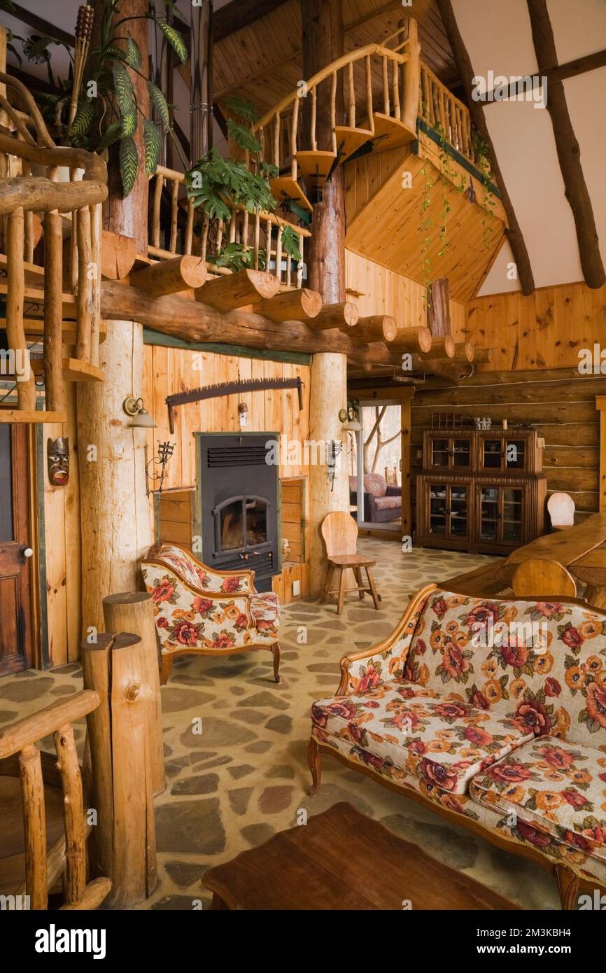 Motifs fleuris fauteuil rembourré et canapé dans la salle de séjour avec  cheminée à l'intérieur d'une cabane rustique en bois Photo Stock - Alamy