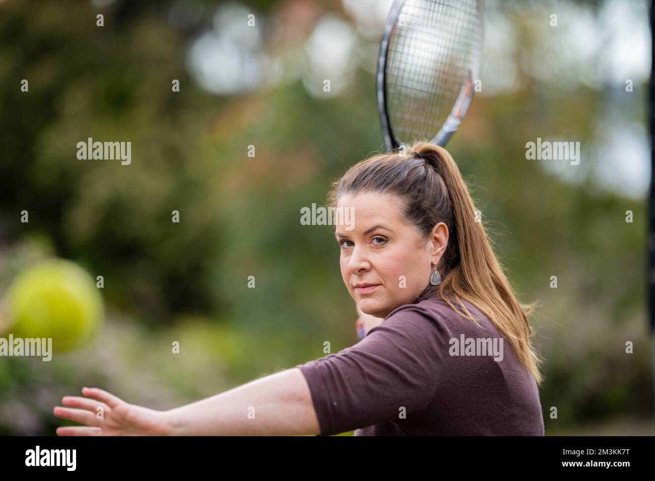 une joueuse de tennis pratiquant les mains avant et frappant des balles de tennis sur un terrain d'herbe en angleterre Banque D'Images