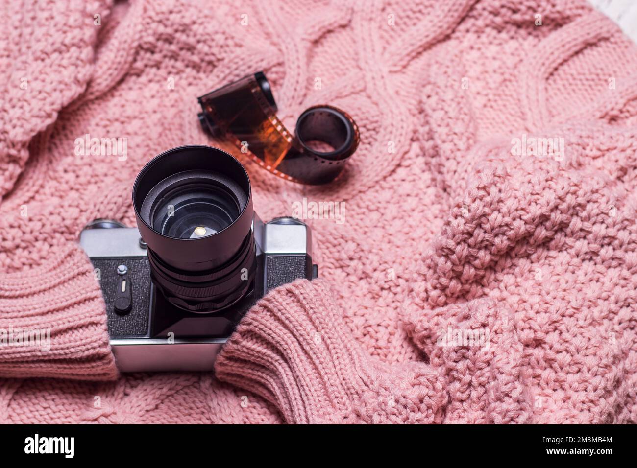 Un ancien appareil photo rétro repose sur un pull en laine rose. Banque D'Images