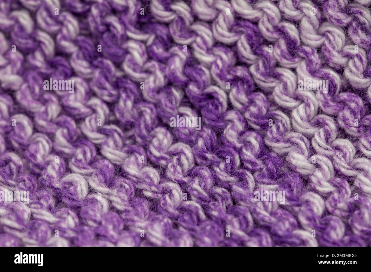 Toile de fond de texture macro abstraite avec effet de flou d'un tissu tricoté à la main de couleur violet et blanc, avec un motif de couture en jarretière Banque D'Images