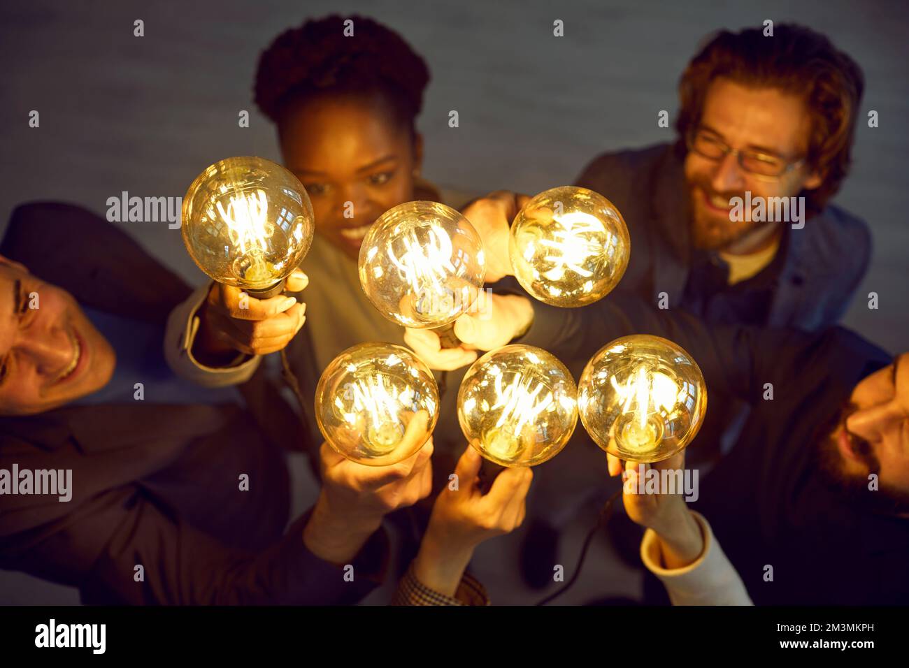 Des ampoules brillantes aux mains de personnes différentes, symbole de nouvelles idées créatives. Banque D'Images