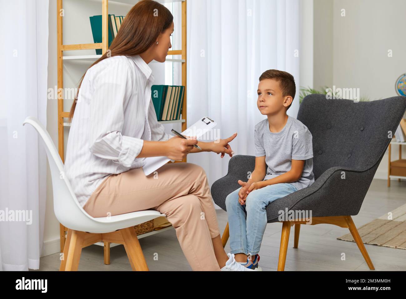 Un garçon d'âge préscolaire pratiquant des sons d'articulation pendant la leçon avec un professeur de orthophoniste. Banque D'Images