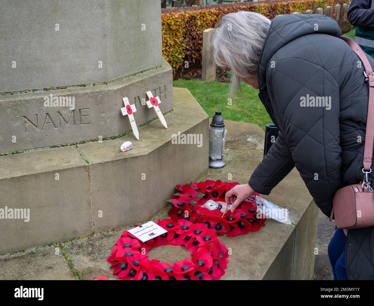 Remembrance Sunday, Royaume-Uni, 2022 ; femme posant une couronne sur la croix du sacrifice, cimetière de Towcester Road, Northampton, Royaume-Uni Banque D'Images