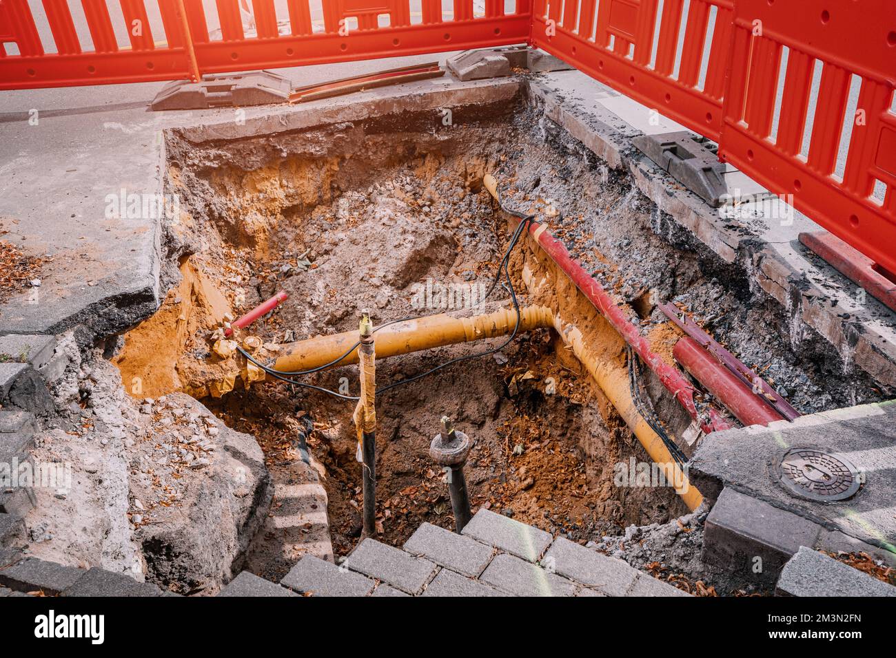 Excavation dans une rue de ville pour remplacer des tuyaux d'eau en plastique ou poser des câbles. Réparation et rénovation sur le site de construction et de développement. Clôture pour saf Banque D'Images