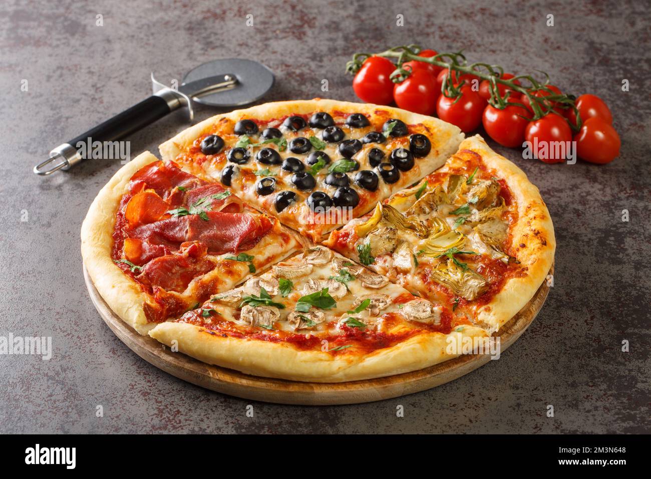 Pizza maison quatre saisons avec tomates, mozzarella, champignons, artichauts, jambon et olives en gros plan sur la table. Horizontale Banque D'Images