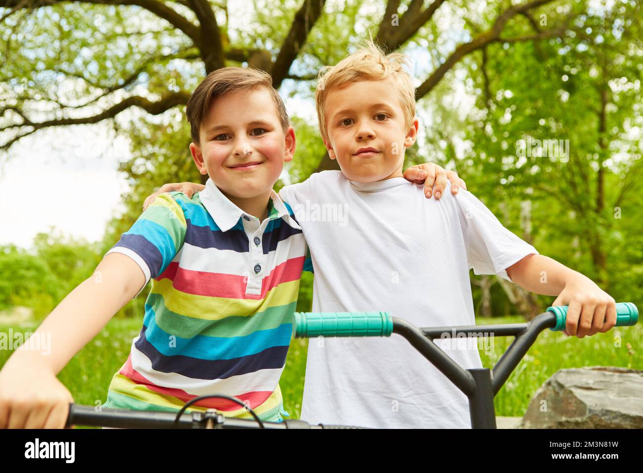Portrait d'amis hommes souriants avec des vélos debout dans le parc pendant les vacances Banque D'Images Portrait d'amis hommes souriants avec des vélos debout dans le parc pendant les vacances Banque D'Images
